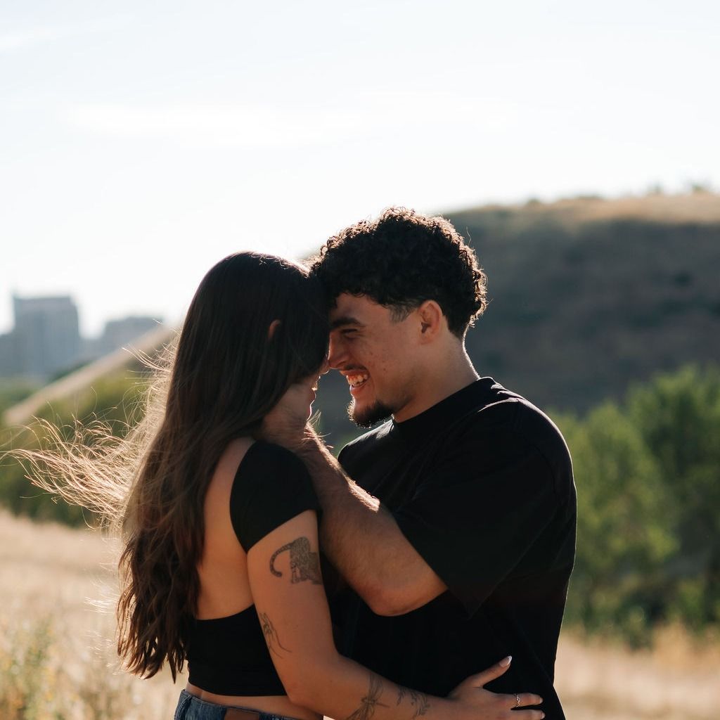 Samia and Antonio embracing on a hillside at sunset