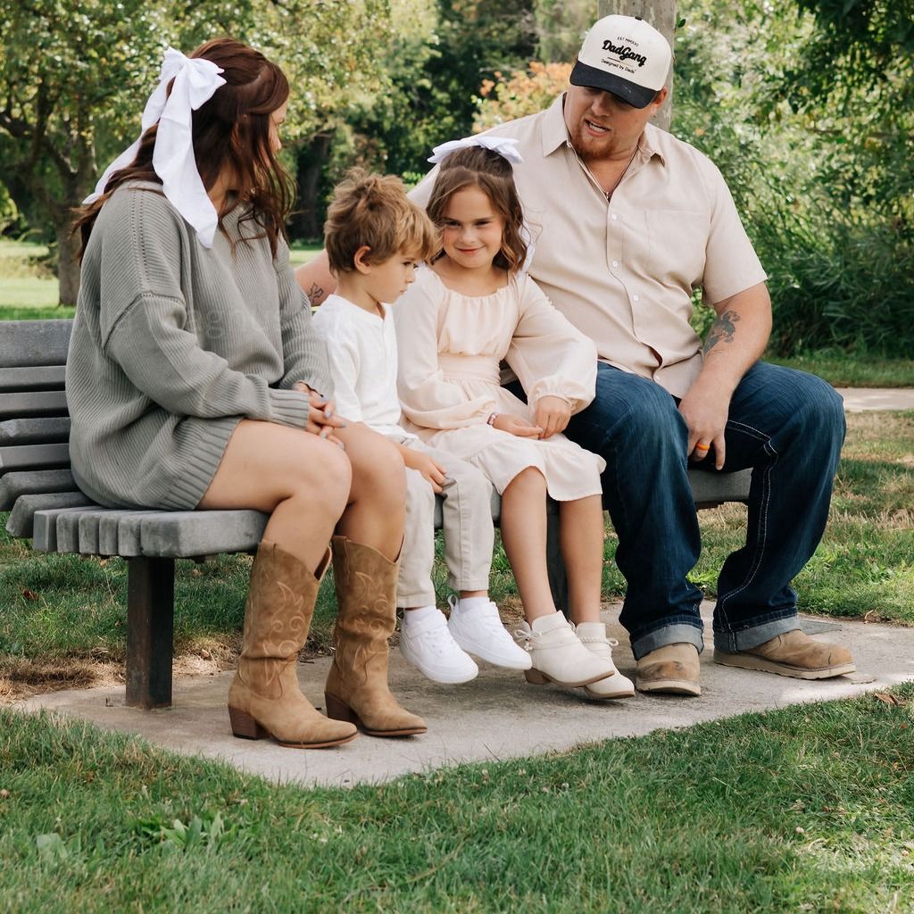 A family of four on a park bench under the trees