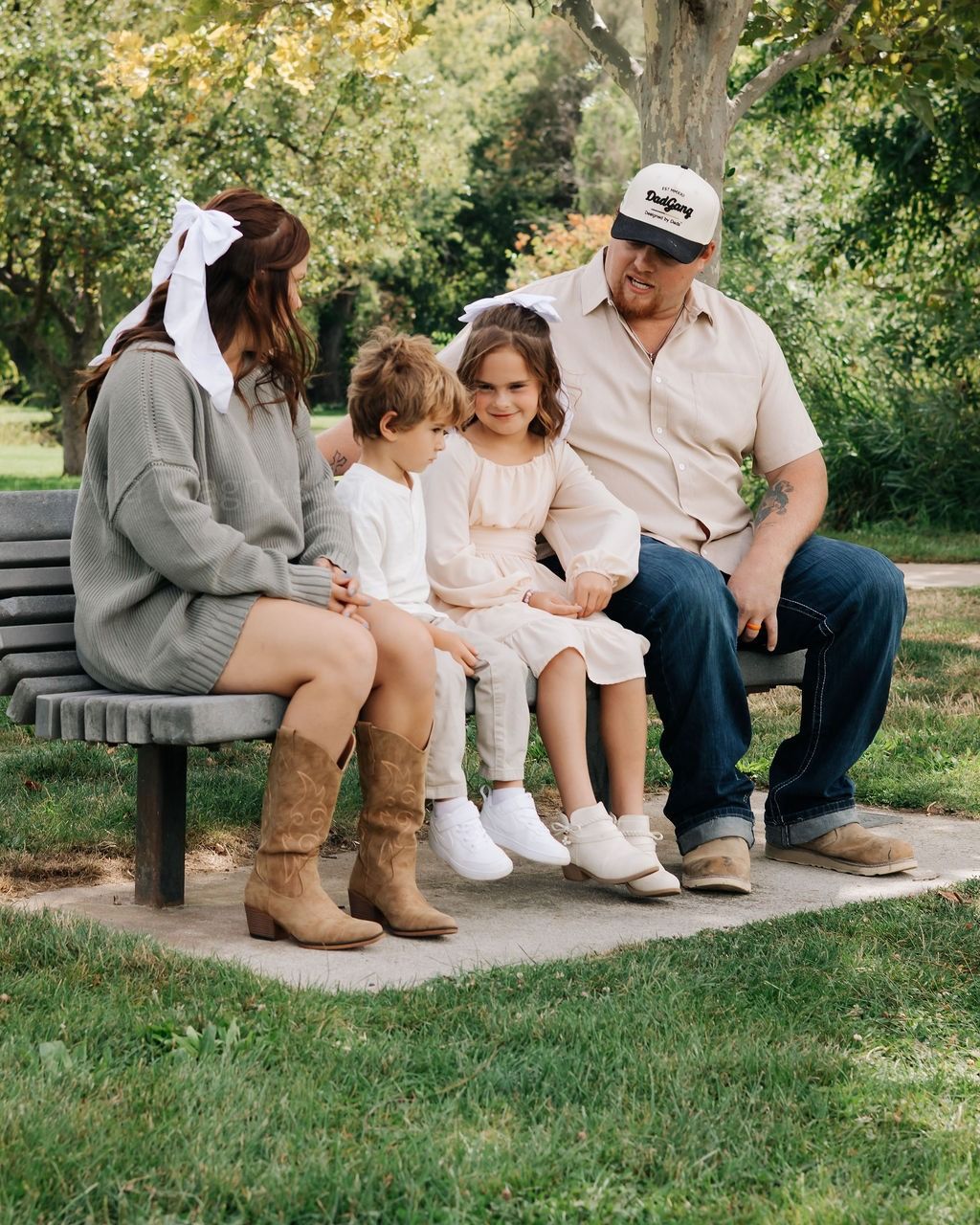 A family of four on a park bench under the trees