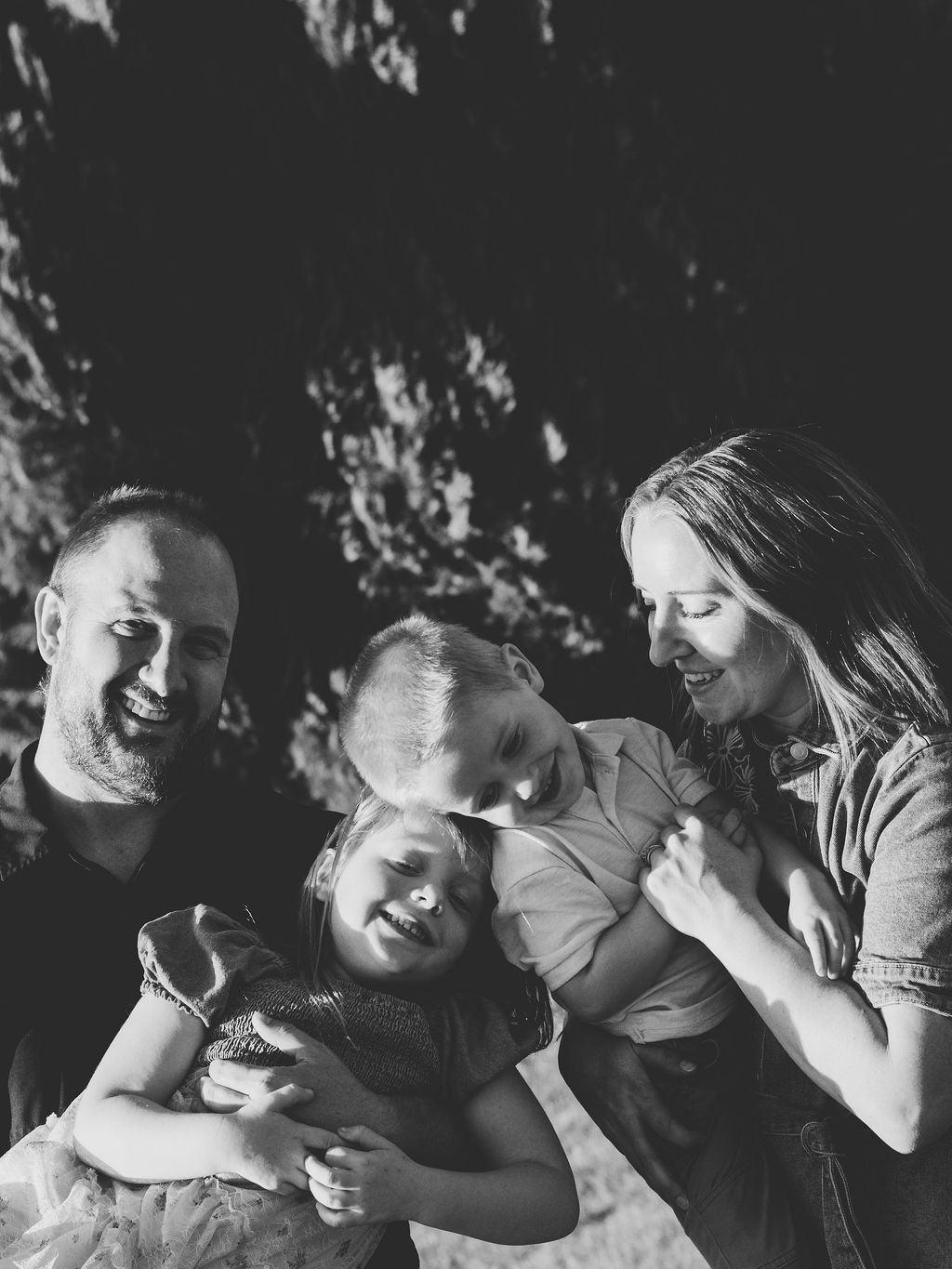 A family of four on a park bench under the trees