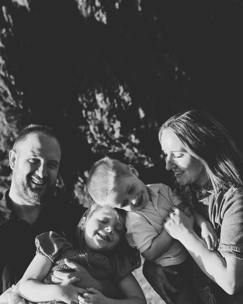 A family of four on a park bench under the trees