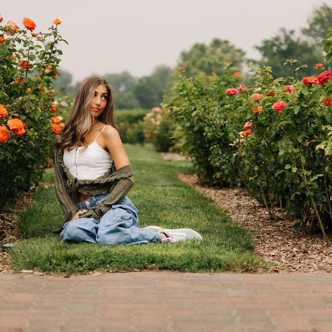 A young woman sitting among orange roses