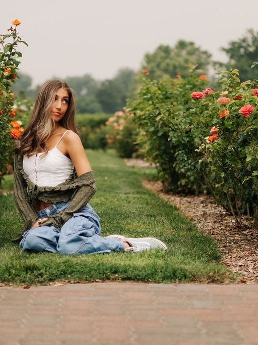 A young woman sitting among orange roses