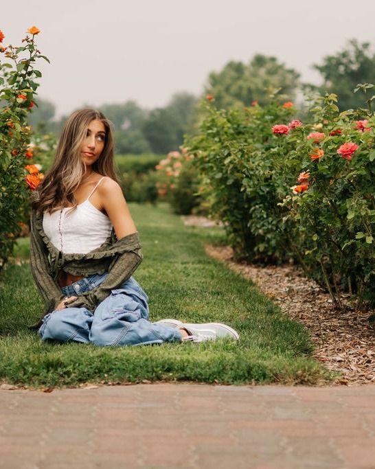 A young woman sitting among orange roses